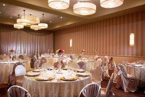 una sala de banquetes con mesas y sillas blancas y lámparas de araña en Sheraton Albuquerque Airport Hotel en Albuquerque
