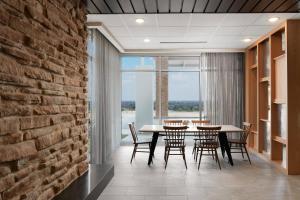 a dining room with a table and chairs and a brick wall at Fairfield Inn & Suites Louisville New Albany IN in New Albany