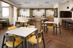 a restaurant with tables and chairs and a kitchen at Fairfield Inn & Suites Louisville New Albany IN in New Albany