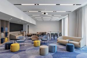 - une salle d'attente avec des chaises et des tables colorées dans l'établissement Courtyard by Marriott Munich Garching, à Garching bei München