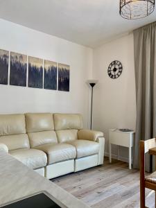 a living room with a couch and a clock on the wall at Pinzolo DOLOMIA apartment in Pinzolo