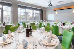 a conference room with tables and green chairs at SpringHill Suites Orange Beach at The Wharf in Orange Beach