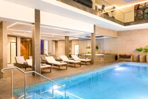 a hotel lobby with a pool and lounge chairs at AC Hotel by Marriott Stockholm Ulriksdal in Solna