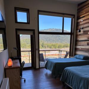 a bedroom with two beds and a balcony with a view at NATIVA MOUNTAIN SUITES in Malalcahuello +79 photos