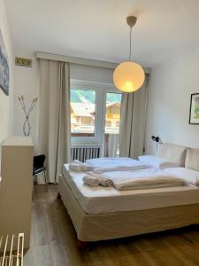 a bedroom with a bed and a large window at Pinzolo DOLOMIA apartment in Pinzolo
