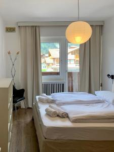 sypialnia z dużym łóżkiem i oknem w obiekcie DOLOMIA APARTMENTS Pinzolo w mieście Pinzolo