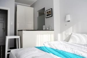 a white bedroom with a bed and a kitchen at Hotel Amber Suite Enklawa dla Dorosłych in Międzywodzie