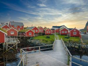a row of red houses next to a dock at Reine Rorbuer - by Classic Norway Hotels in Reine