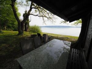 einen Tisch und Stühle mit Blick auf das Wasser in der Unterkunft Häuschen direkt am See in Reichenau