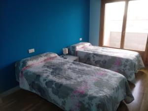 two beds in a room with blue walls and a window at Skyline León con opcion de Parking in León