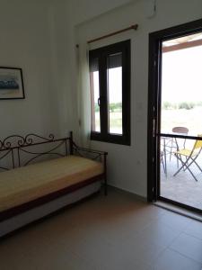 a bedroom with a bed and a balcony with a table at Red Village Limnos in Moúdhros