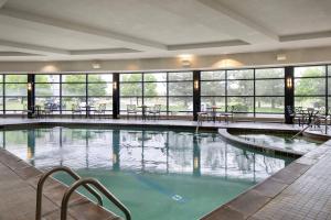 a large swimming pool with tables and chairs in a building at Denver Airport Marriott at Gateway Park in Aurora