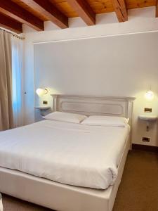 a bedroom with a large white bed with two lamps at Alla Corte Rossa in Venice