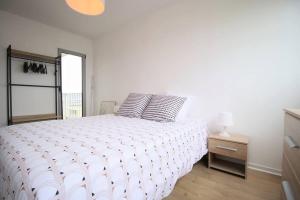 1 dormitorio con 1 cama blanca y 2 almohadas en Ravissant trois pièces : Proche des Quais !, en Rouen