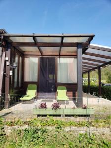 eine Terrasse mit zwei grünen Stühlen und ein Haus in der Unterkunft Chalet 176 in Durbuy