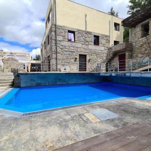 ein großer blauer Swimmingpool vor einem Gebäude in der Unterkunft Quinta do Avô - Casa de Campo in Terras de Bouro