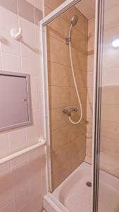 La salle de bains est pourvue d'une douche et d'une baignoire avec douche. dans l'établissement VVF Plaine d'Alsace Obernai Strasbourg, à Obernai