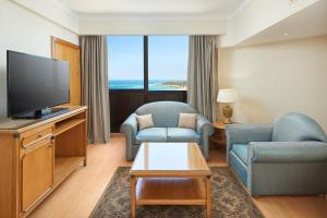 a living room with a tv and a couch and chairs at Sheraton Montazah Hotel in Alexandria