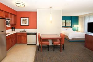 a kitchen with a table and a bedroom with a bed at Residence Inn by Marriott Newark Silicon Valley in Newark