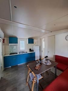 uma cozinha com armários azuis, uma mesa e um sofá vermelho em Borić Mobile Homes in Bijela Uvala and Zelena Laguna em Porec