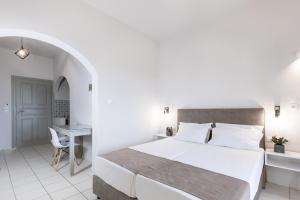 a white bedroom with a bed and a desk at Keti Apartments in Adelianos Kampos