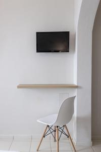 a white chair and a television on a wall at Keti Apartments in Adelianos Kampos