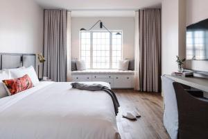 a bedroom with a large white bed and a window at The Alida, Savannah, a Tribute Portfolio Hotel in Savannah