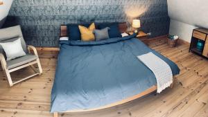 um quarto com uma cama azul e uma cadeira em Dižbraki em Ventspils