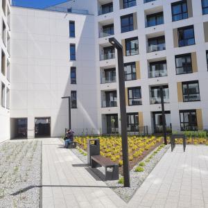 a person sitting on a bench in front of a building at Apartament Centrum Pestige Mińsk in Mińsk Mazowiecki