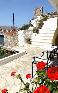 a bench and red flowers on a patio with stairs at Thea in Symi