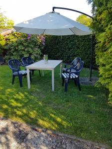 a white table and chairs under an umbrella at Ferienhaus Brungers in Südbrookmerland