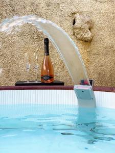 una bottiglia di vino e due bicchieri in piscina di Villa Boeddu, relax tra mare e campagna ad Alghero