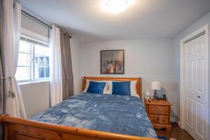 Un dormitorio con una cama con sábanas azules y una ventana. en Two Bedroom Apartment Near St John's Airport, en St. John's
