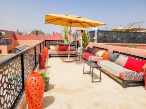 a patio with couches and an umbrella on a balcony at Riad Dar Chadia in Marrakesh