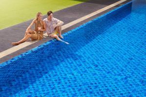 a man and woman sitting next to a swimming pool at Fairfield by Marriott Surabaya in Surabaya