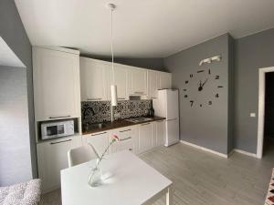 a kitchen with white cabinets and a clock on the wall at GIL Apartments, Volodimirskaja 90.212 - Majetok Bozdosh in Uzhhorod +4 photos