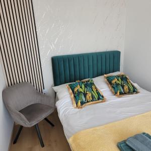 łóżko z zielonym zagłówkiem i krzesłem w obiekcie Apartament Centrum Pestige Mińsk w mieście Mińsk Mazowiecki