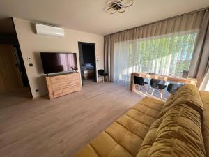 ein Wohnzimmer mit einem Sofa und einem Flachbild-TV in der Unterkunft Optimus Residence in Balatonföldvár