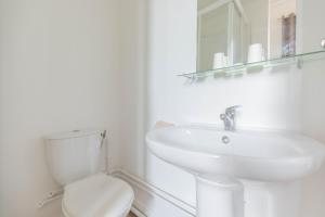 a white bathroom with a sink and a toilet at Hôtel Le Paris Brest in Lens