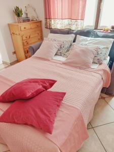 - 2 lits avec des draps et des oreillers rouges et blancs dans l'établissement Casa Pepolina, zona tranquilla, piano terra con parcheggio, à Malesco