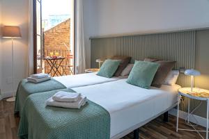 two beds in a room with a large window at Habitat Apartments Barcelona Balconies in Barcelona