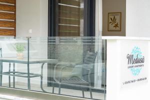 einen Glasbalkon mit einem Tisch und einem Stuhl in der Unterkunft Medusa Luxury Apartments in Néa Péramos