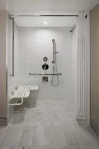 a white bathroom with a bench and a shower at Delta Hotels by Marriott Saskatoon Downtown in Saskatoon