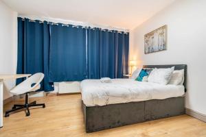 a bedroom with a bed and a desk and blue curtains at Double Bed Room in Flat near Birmingham City Centre in Birmingham
