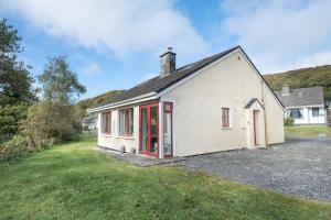 une petite maison blanche avec des portes rouges dans une cour dans l'établissement Cottage 420 - Clifden, à Clifden
