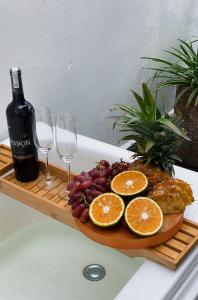 a plate of fruit and wine glasses on a cutting board at MIHA Villa & Stay in Cái Răng