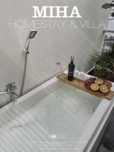 a bath tub with a tray of champagne and wine glasses at MIHA Villa & Stay in Cái Răng