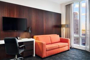 um quarto de hotel com uma cadeira laranja e uma televisão em Courtyard by Marriott Long Island City/New York Manhattan View em Queens