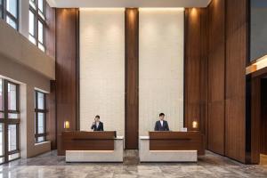 dos personas sentadas en escritorios en un vestíbulo en Fairfield by Marriott Shanghai Hongqiao NECC, en Shanghái