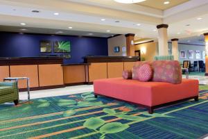 a waiting area with a red couch in a waiting room at Fairfield Inn and Suites Flint Fenton in Fenton